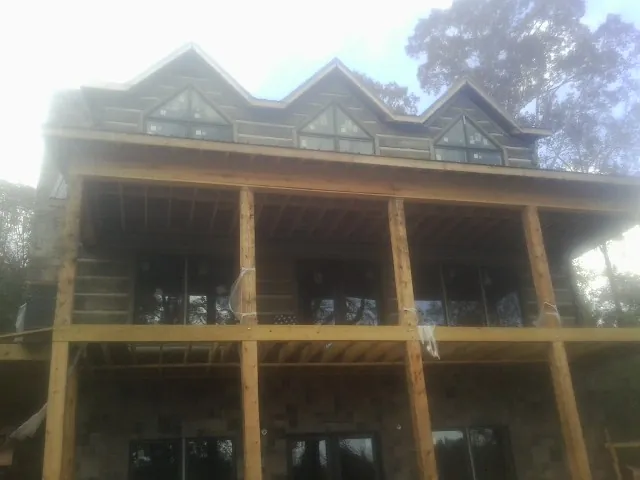 Dormers and porch framing on a large log home under construction — Roof Coating work by our crew in Brooklyn