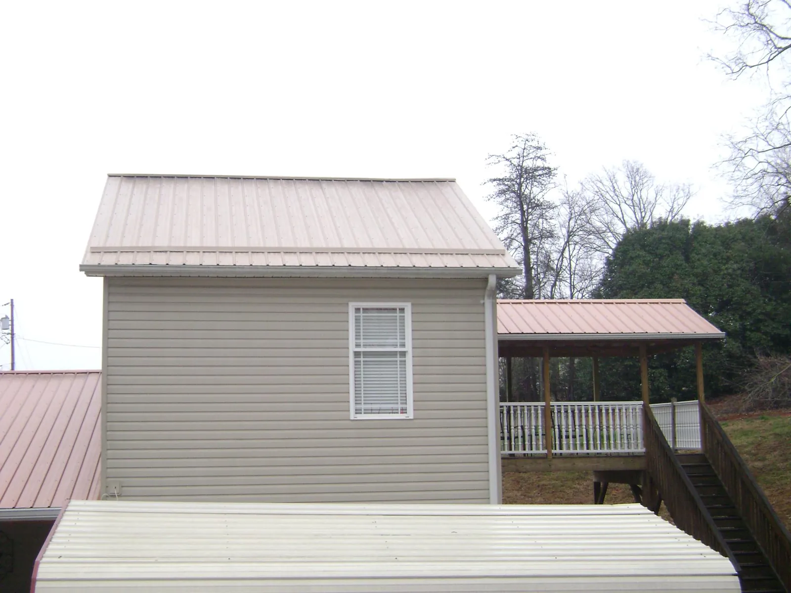Tan metal roofs on a two story addition and attached porch, from a Roof Replacement job in Brooklyn